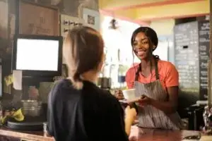 jovem recebendo café em uma cafeteria para ilustrar texto de alimentação em